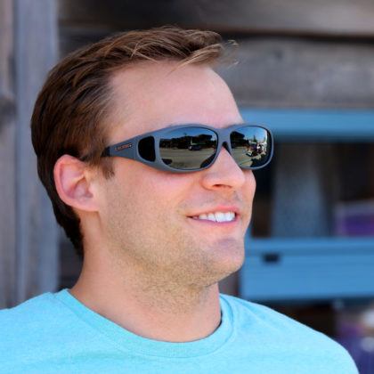 Man wears slate gray sunglasses designed to fit over regular eyeglasses.